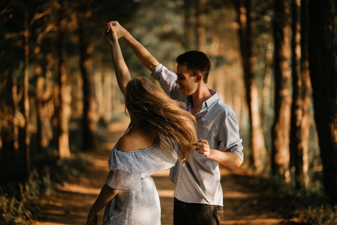 Par danser sammen på en skovsti med hænderne løftet