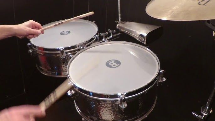 Hænder spiller på en tromme og et percussion-sæt med bækken